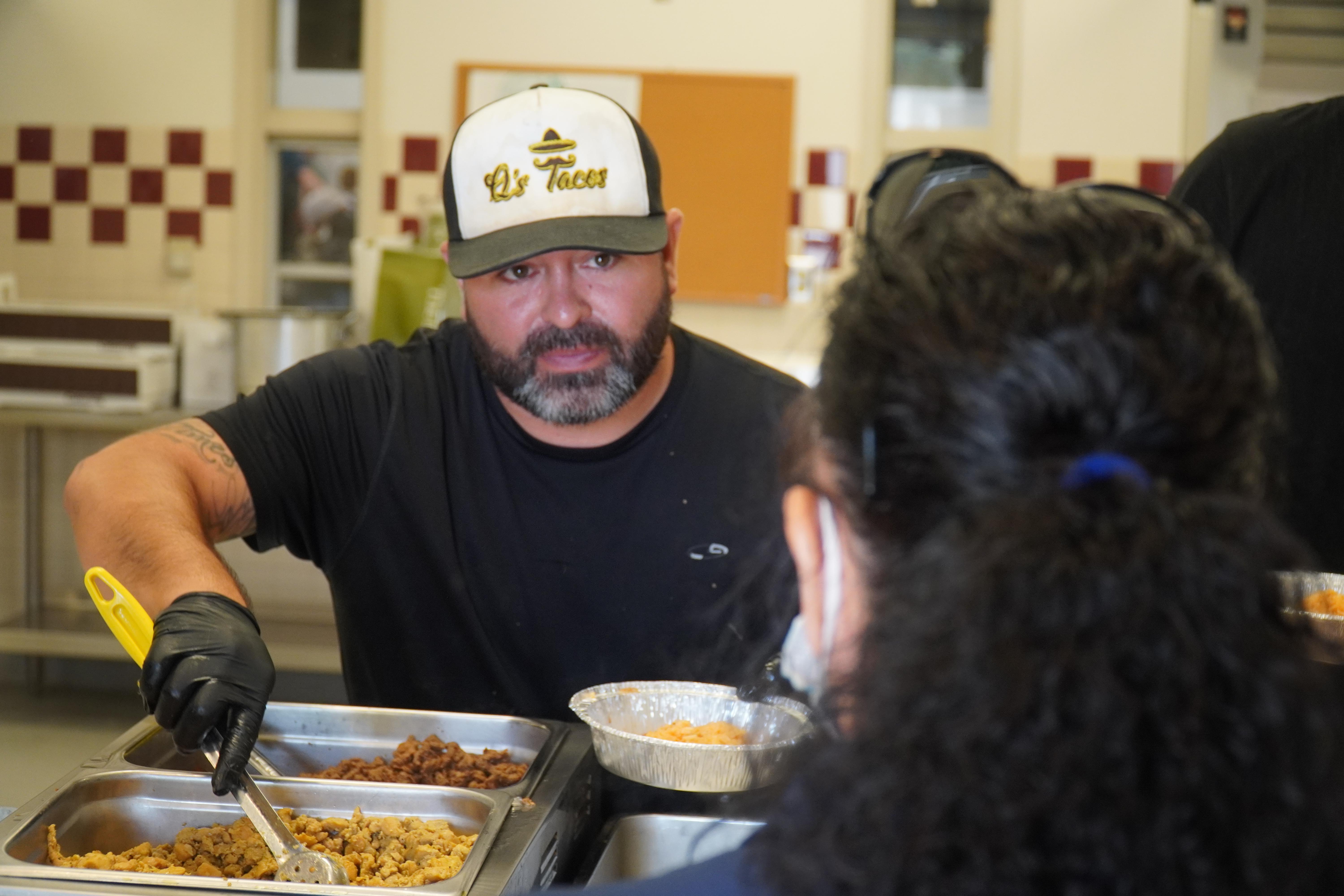 man with hat serving mexican food